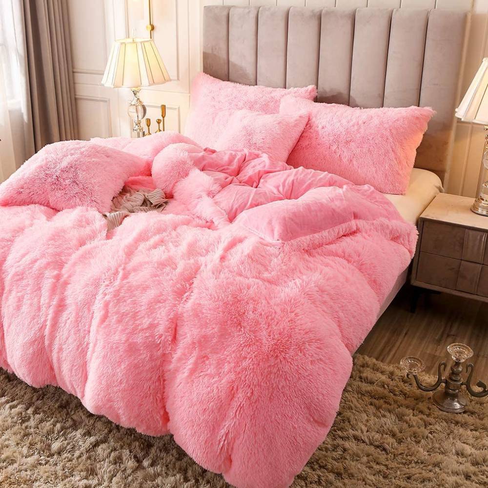 Pink fluffy bedding with matching pillows on a bed